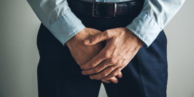 a man patiently holding his crotch