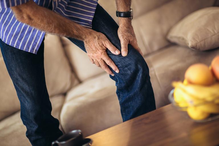 a middle-aged man grabbing his bad knee in pain